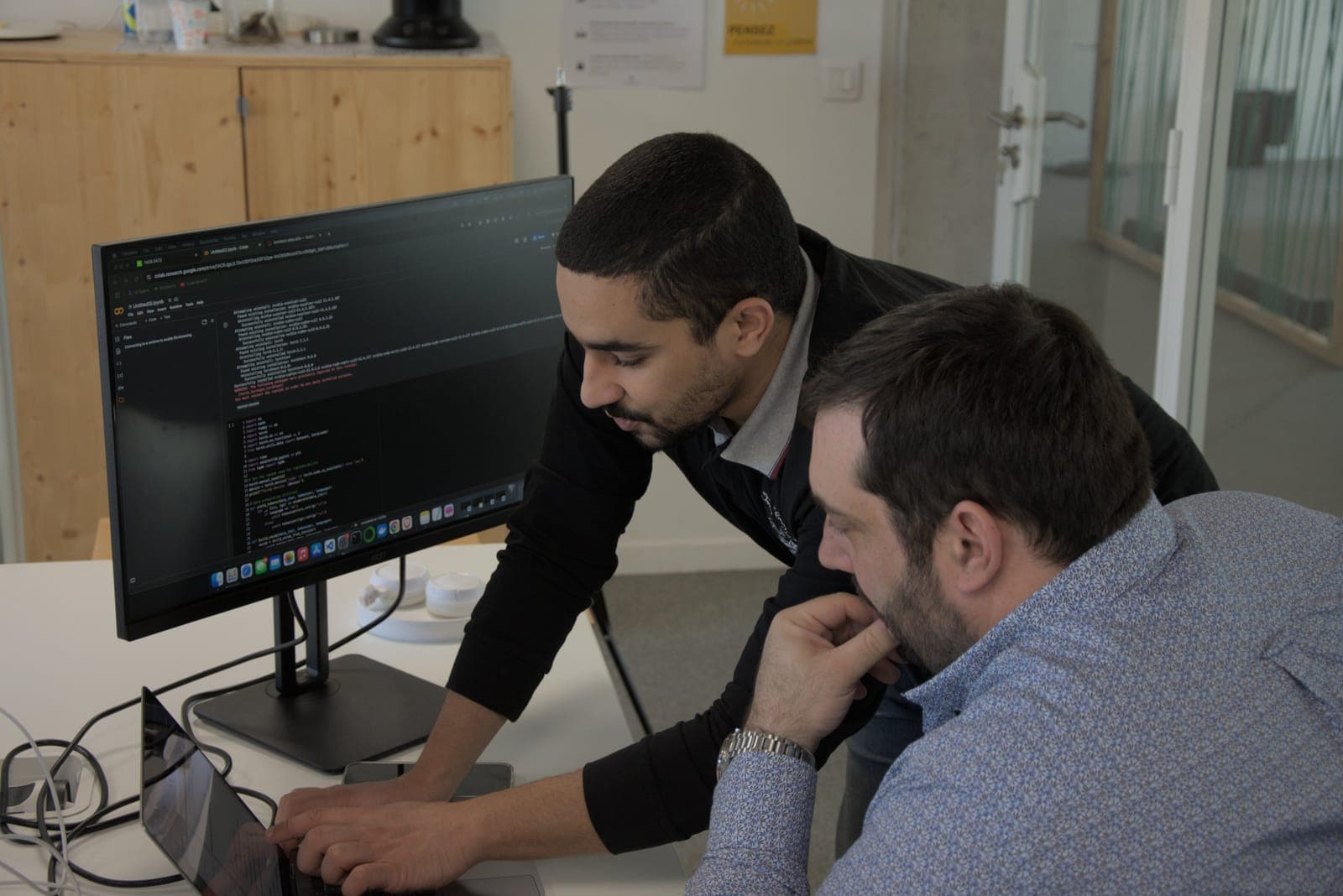 Two colleagues analysing code on a screen
